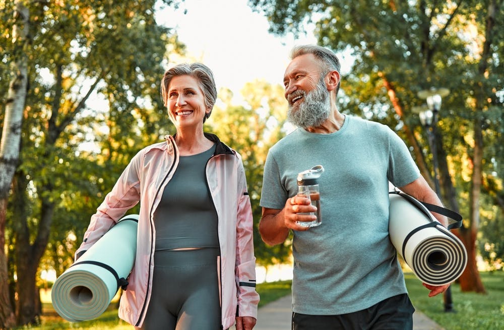 Older couple with yoga mats walking outdoors