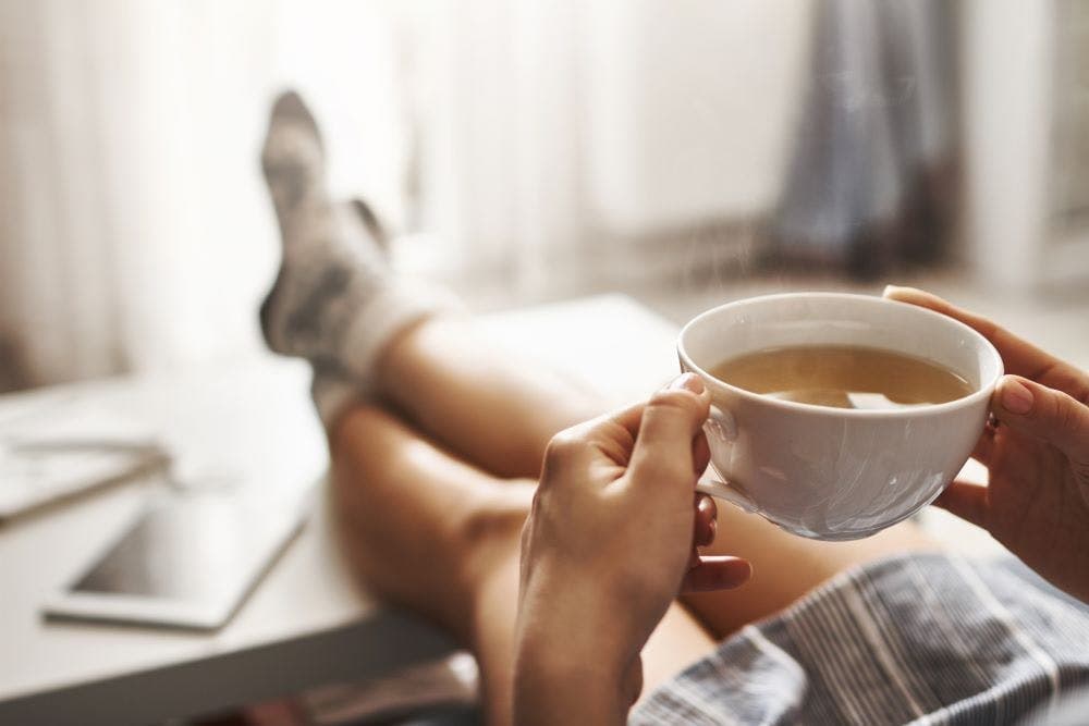 Woman lying on couch, drinking hot tea and enjoying morning. 