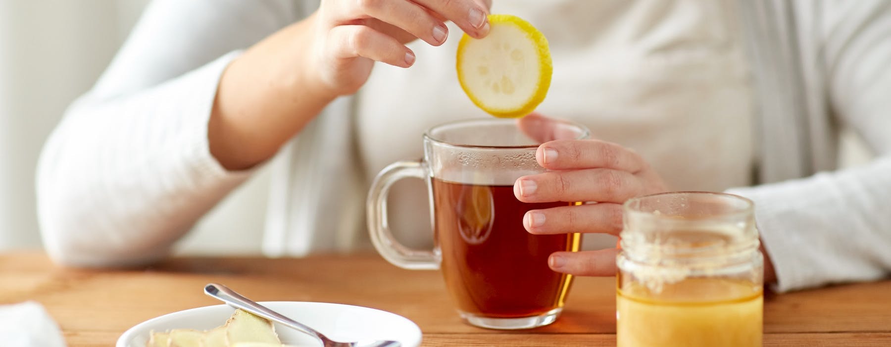 A woman preparing tea with lemon