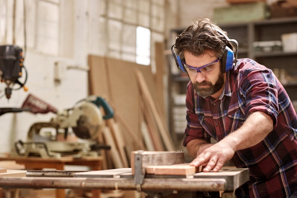 A carpenter cutting wood with safety goggles 