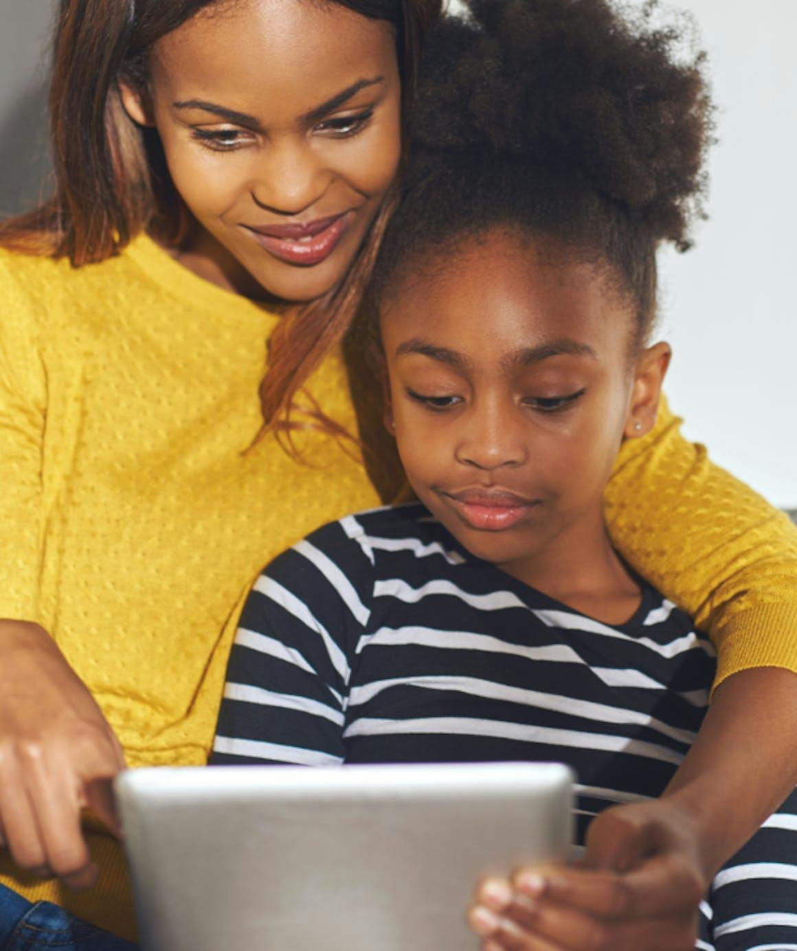 A mother and daughter use a tablet to speak with a provider